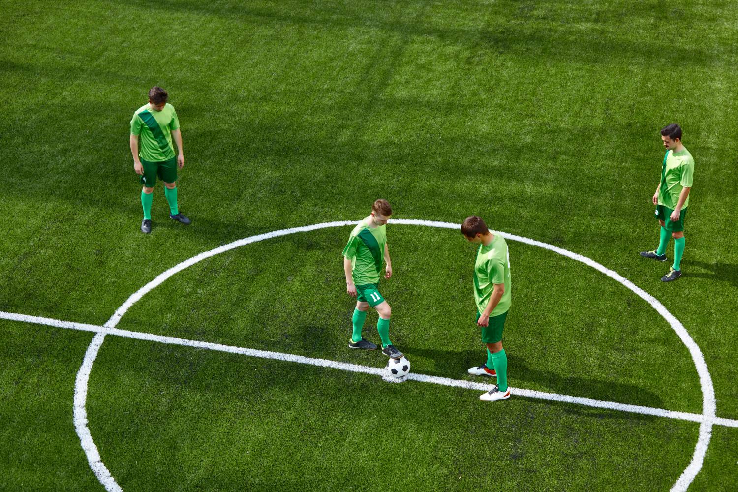 Thq legs of soccer football player training football on green grass field